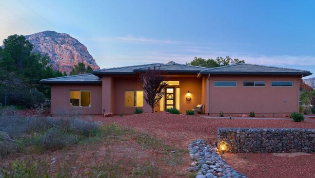 A two-story house with a stone pathway leading to the entrance, surrounded by a natural landscape with a mountain in the background. - Spacious Home with Thunder Mountain Views! (Sedona)