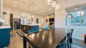 A modern kitchen with a central island, stainless steel appliances, and pendant lighting. - Spacious Home with Thunder Mountain Views! (Sedona)
