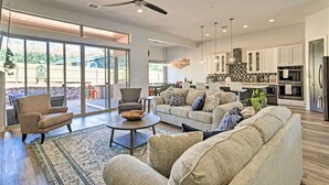 A spacious living room with a large sofa, a coffee table, and a dining area with a kitchen in the background. - Spacious Home with Thunder Mountain Views! (Sedona)