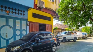 A black car parked on a cobblestone street, with buildings in the background. - Hotel O Guesthouse Rantang (Medan)
