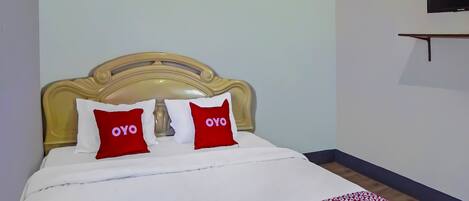 A bed with a headboard, two pillows with the word "OYO" on them, and a red and white blanket.