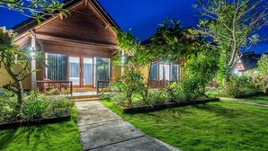 Een huis met twee verdiepingen, van hout, met een verzorgd gazon en een pad dat naar de ingang leidt.