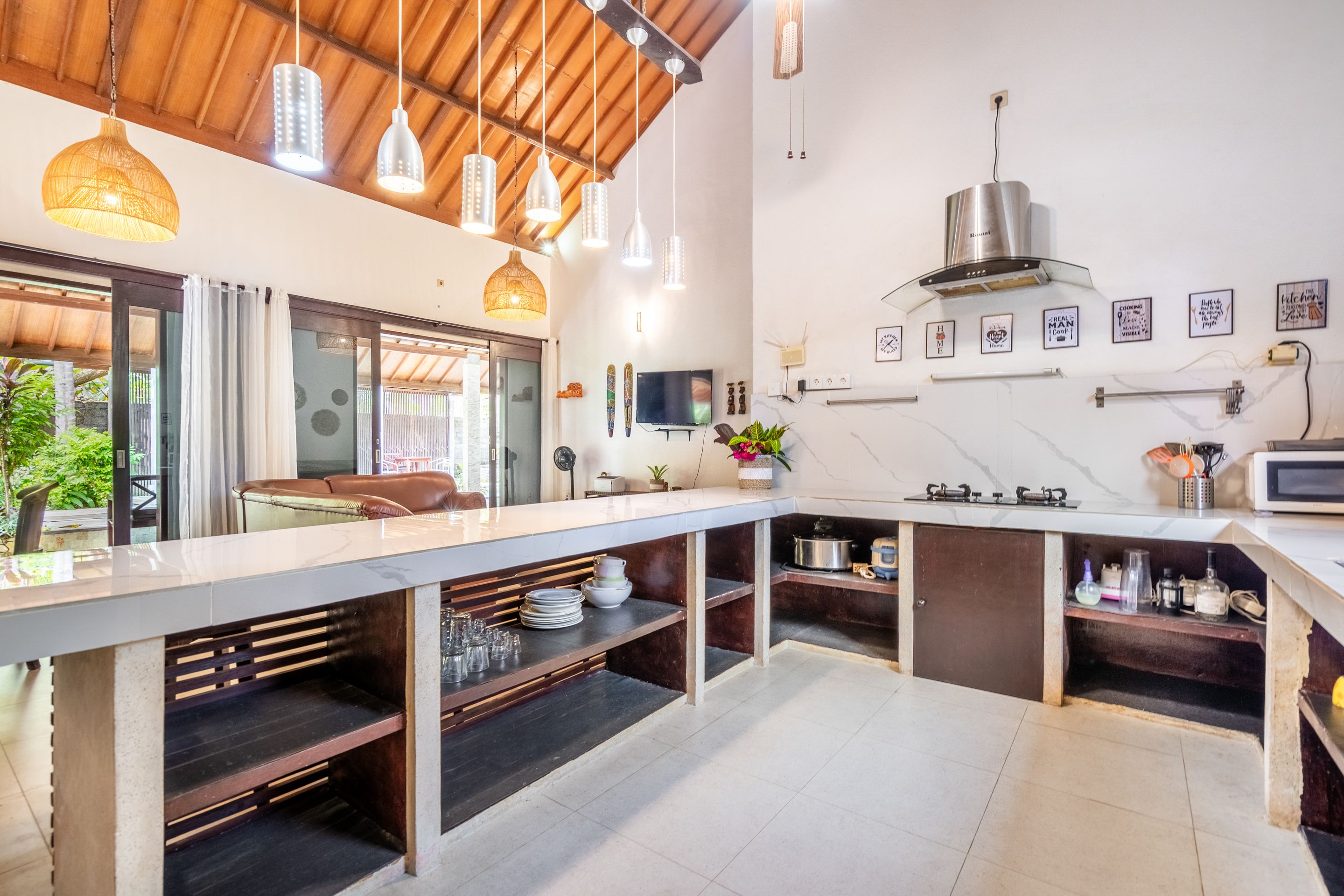 A modern kitchen with a long counter, built-in shelves, and a stainless steel range hood.