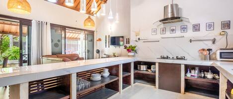 A modern kitchen with a long counter, built-in shelves, and a stainless steel range hood.