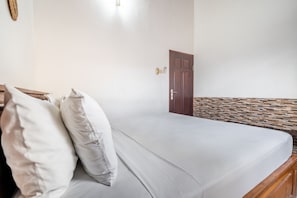 A room with a bed, a wooden headboard, a door, and a wall with a textured pattern.