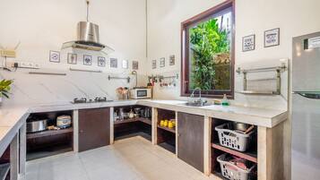 Een moderne keuken met een inbouwfornuis, een spoelbak en een raam met uitzicht op groen.