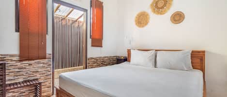 A bedroom with a wooden bed, a nightstand, a wall-mounted decorative item, and a window with blinds.