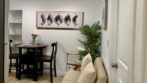 A dining area with a table, chairs, and a wall-mounted artwork depicting phases of the moon. - Private 1BR Suite w Full Kitchen & Laundry (Hayward)