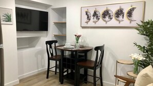 A dining area with a table and chairs, a wall-mounted TV, and a framed artwork above the table. - Private 1BR Suite w Full Kitchen & Laundry (Hayward)
