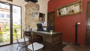 Una habitación con escritorio, dos sillas, espejo y puerta.