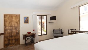 Un dormitorio con cama, escritorio, silla, televisor y una puerta.