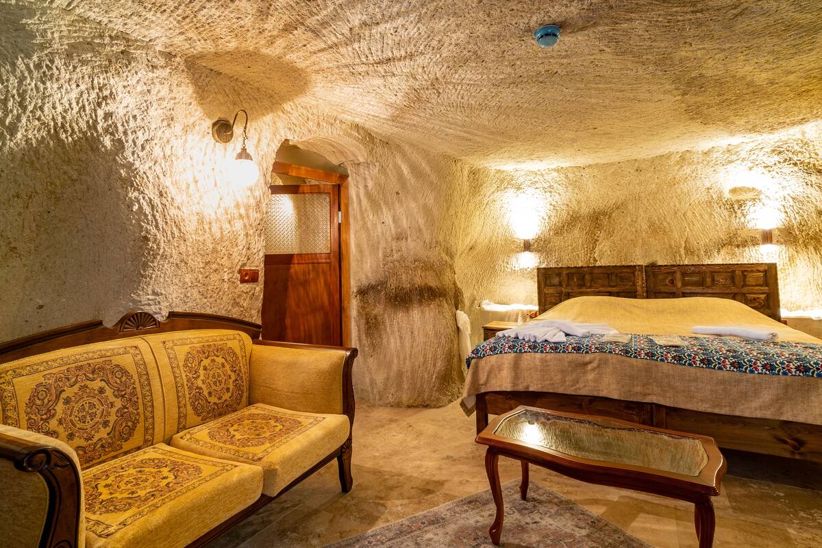 A room with a wooden bed, a sofa, and a small table.