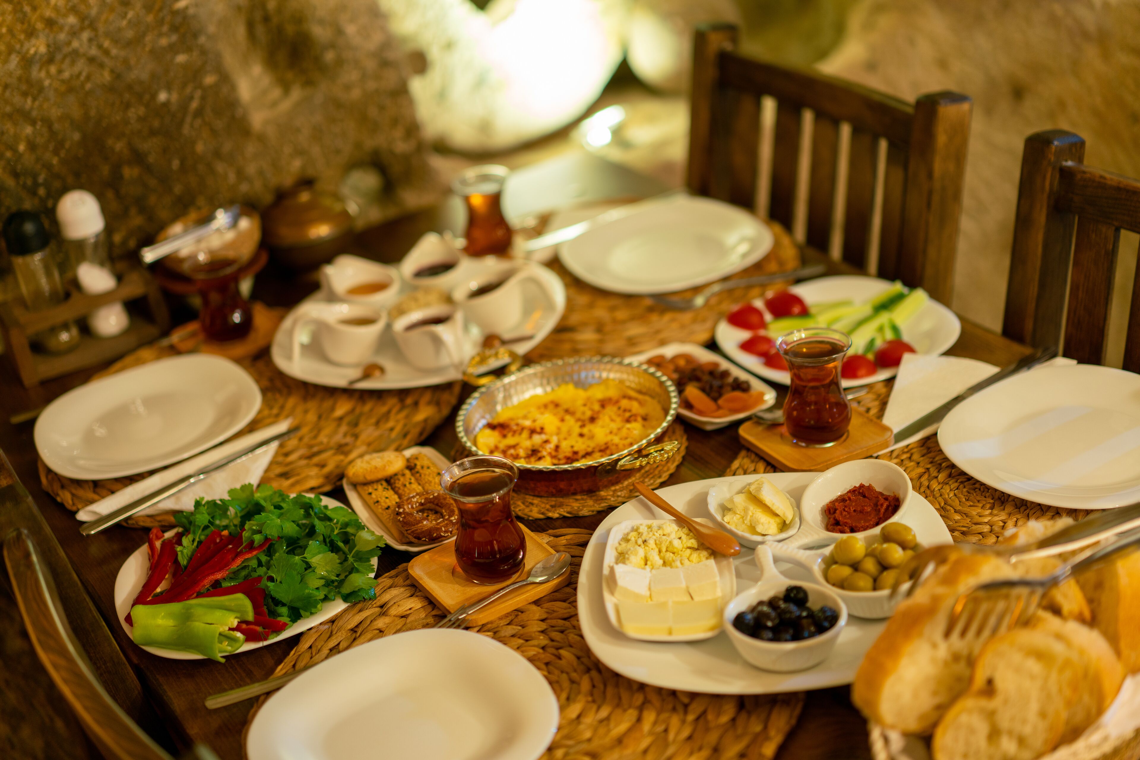 A table set for a meal with various dishes, including bread, cheese, olives, and vegetables.