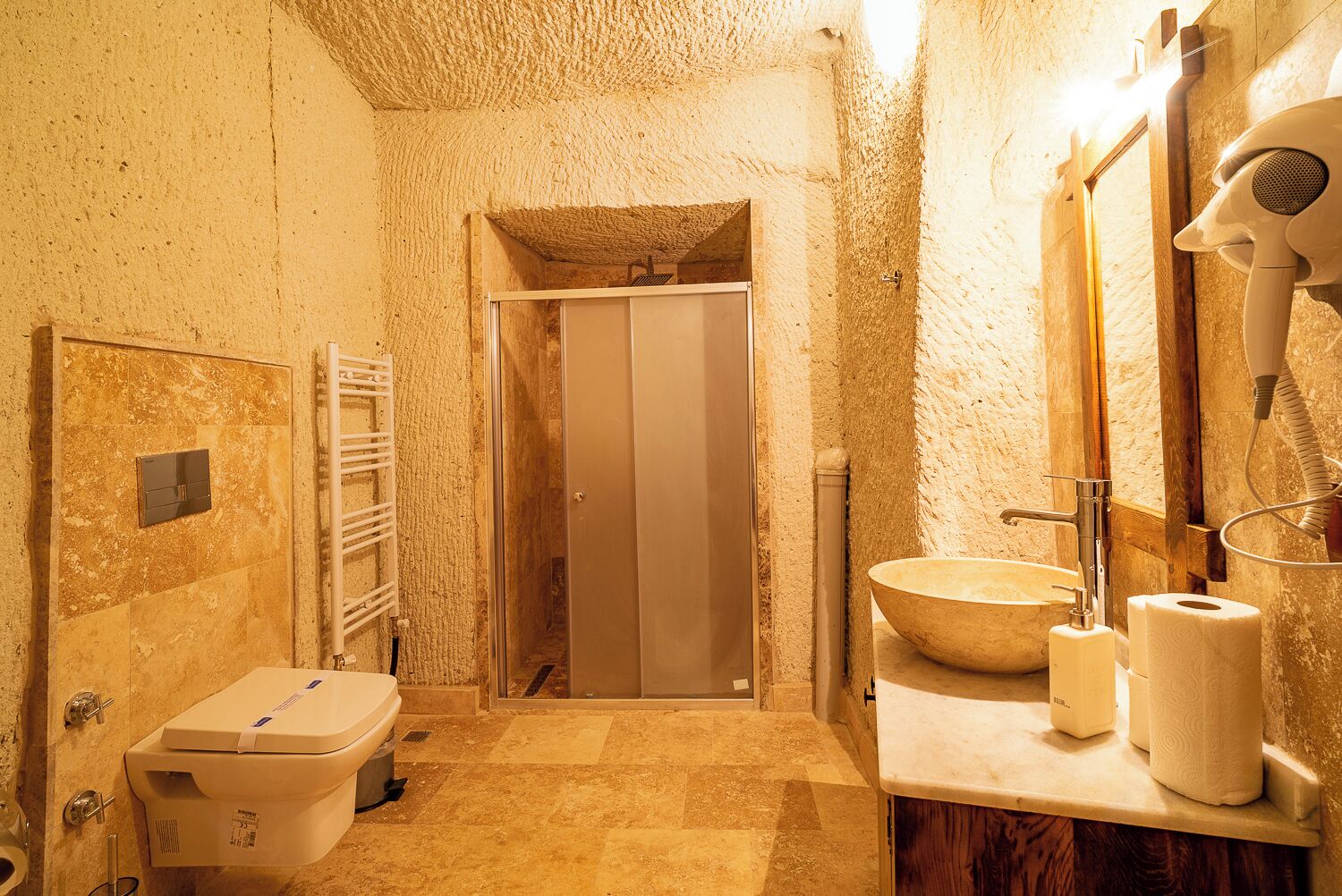Un baño con un espejo grande, un lavabo, un inodoro y una zona de ducha.