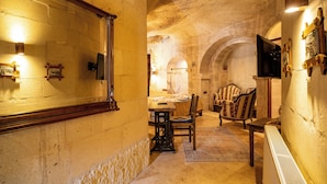 Une pièce aux murs de pierre, avec un lit, une table et deux chaises.