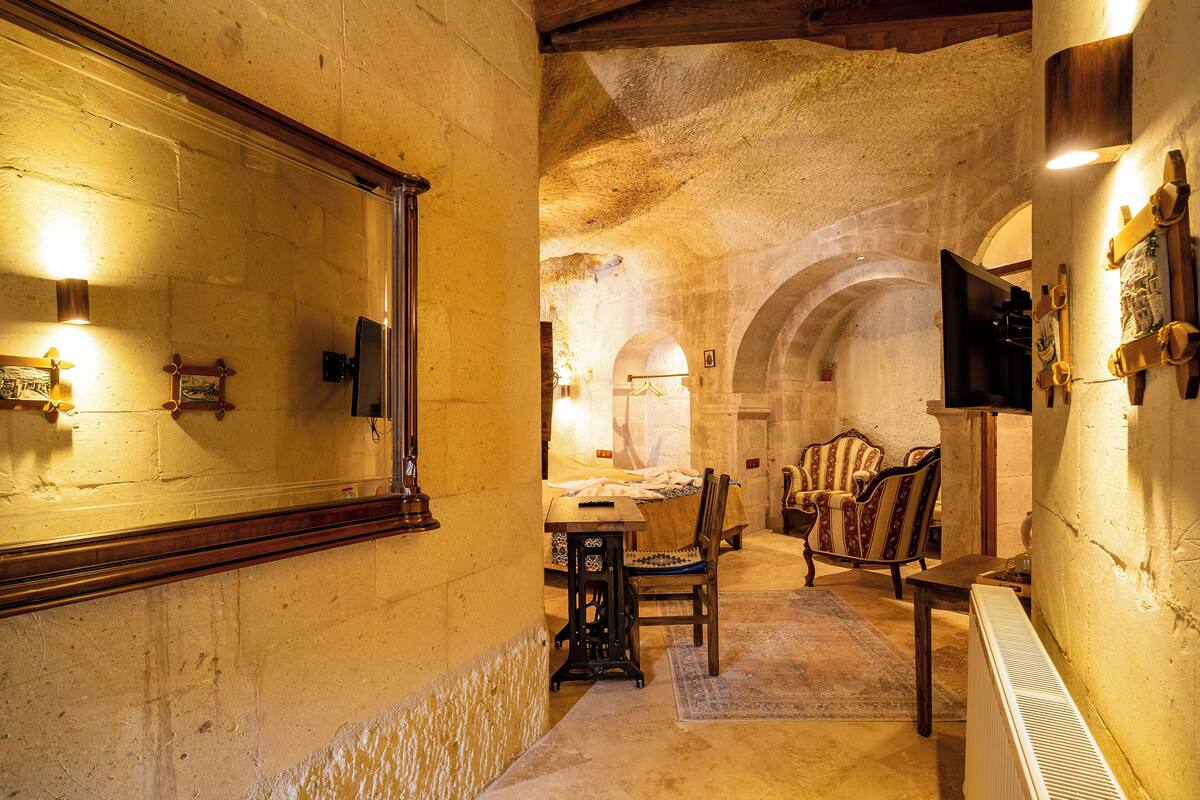 A stone-walled room with a bed, a table, and two chairs.