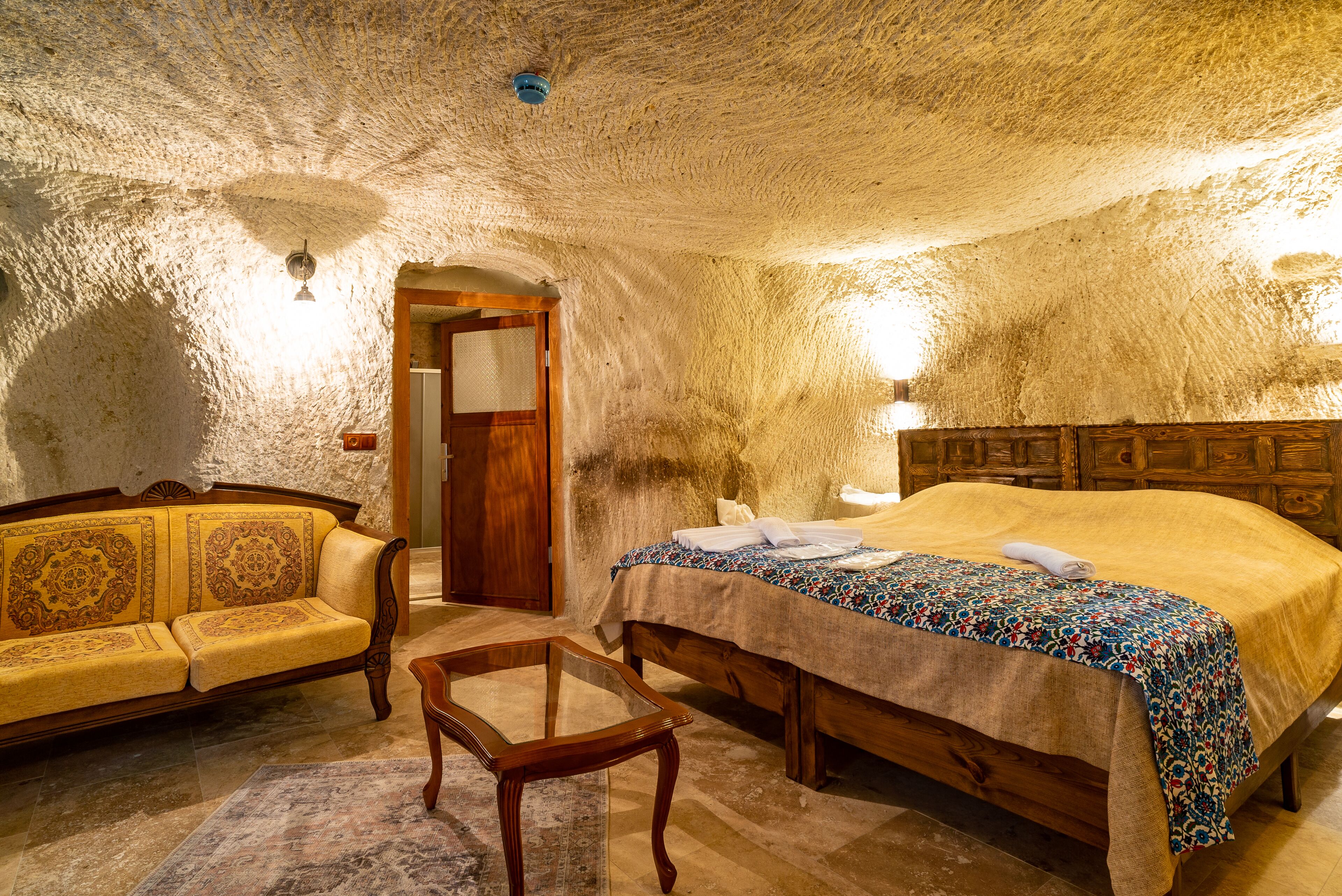 A room with a bed, a sofa, a small table, and a door.