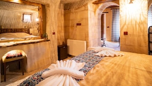Une pièce avec un grand lit, un banc en bois, un radiateur et un miroir au mur.