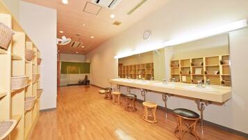 A bathroom with wooden floors, a large mirror, and shelves with baskets.
