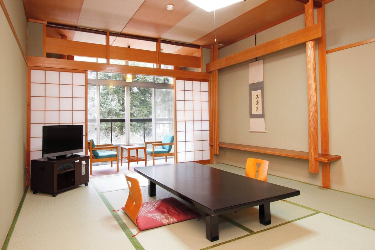 A traditional Japanese-style room with tatami flooring, a low table, and sliding doors.