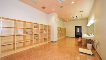 A hotel lobby with wooden shelving units, a reception desk, and a bathroom with a sink and mirror.