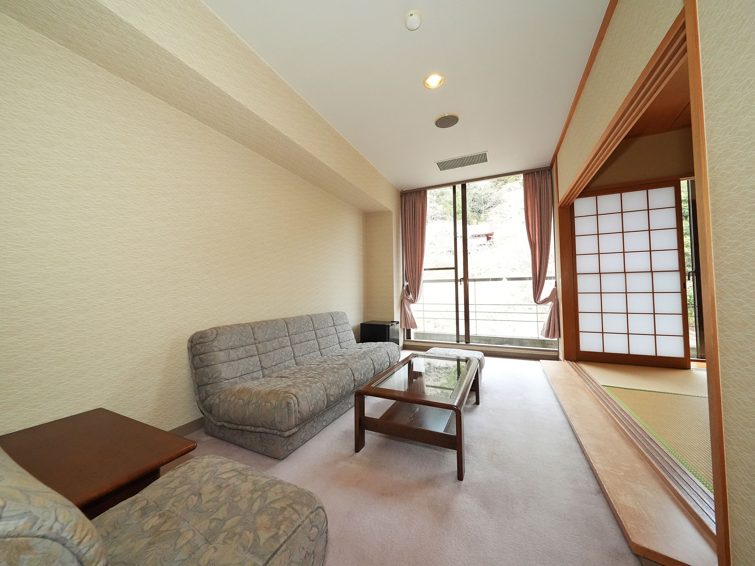 A living room with a sofa, a coffee table, and a sliding door leading to a balcony.