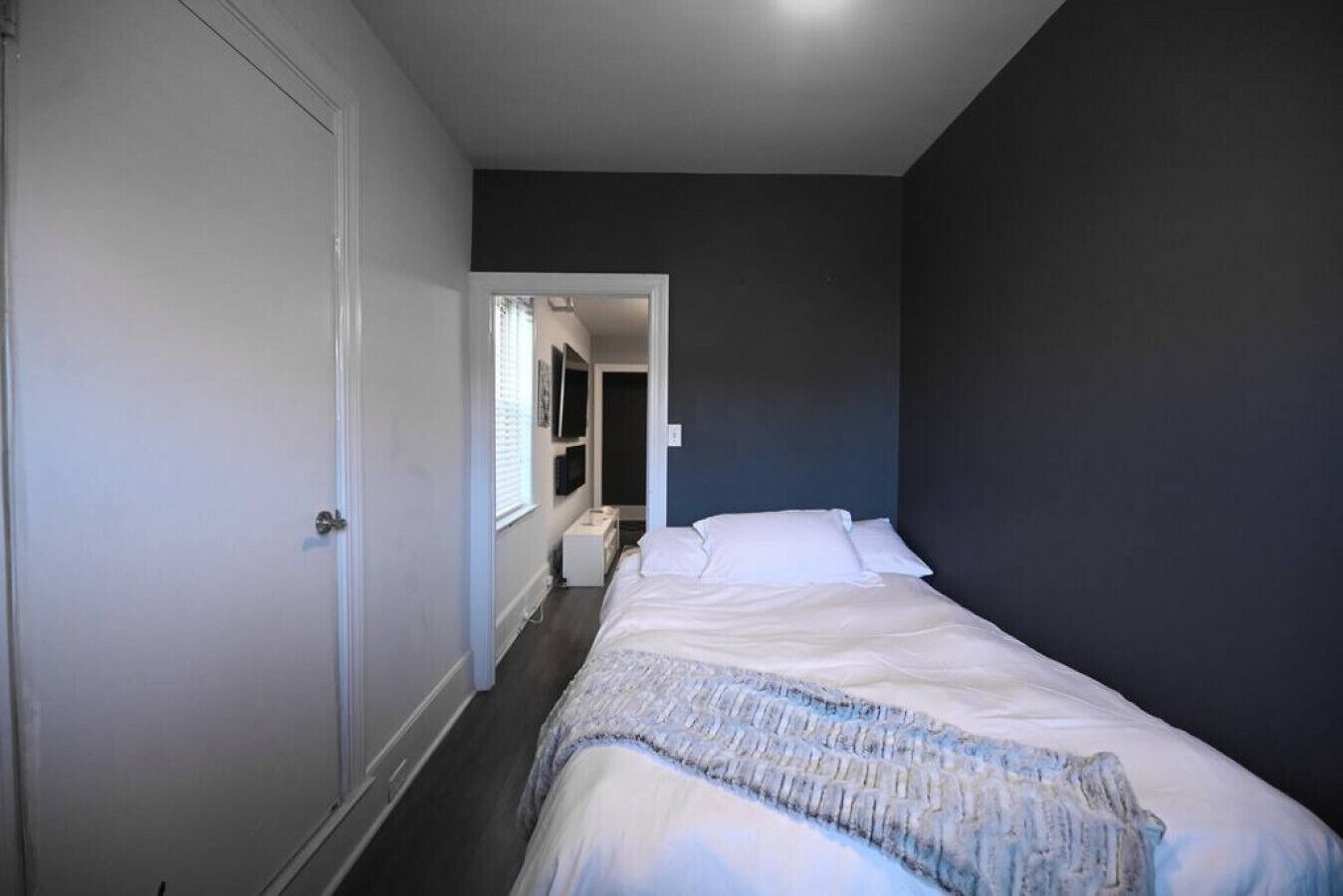 A bedroom with a bed, a wardrobe, and a door leading to another room.