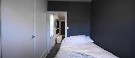 A bedroom with a bed, a wardrobe, and a door leading to another room.