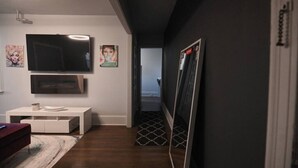 Um corredor moderno com televisão de tela plana, um console branco e um espelho.