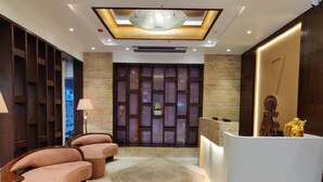 Un área de recepción moderna con suelo de mármol, un mostrador de recepción y una zona de estar con sillones acolchados.