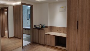 Un baño moderno con muebles de madera, zona de ducha con azulejos de mármol y lavabo con espejo.