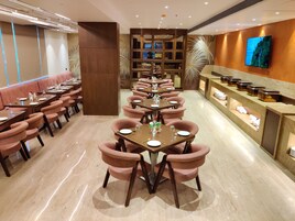 Un restaurante con una larga mesa dispuesta para comer, asientos acolchados y una zona de bufé.