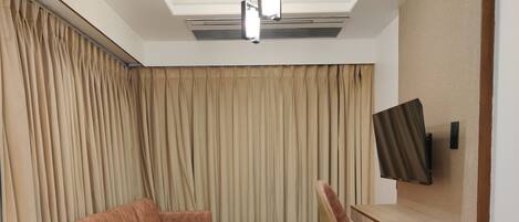 Una sala de estar moderna con un sofá modular, una mesa de centro redonda y un televisor montado en la pared.