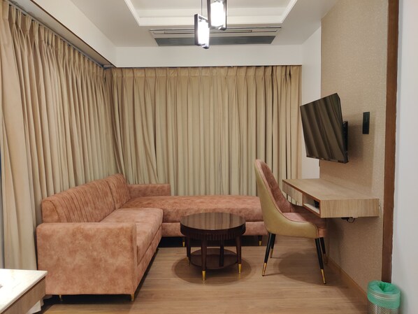 A modern living room with a sectional sofa, a round coffee table, and a TV mounted on the wall.