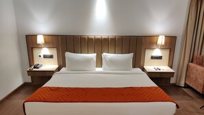 Habitación de hotel con una cama grande, dos mesitas de noche con lámparas, un teléfono y un control remoto.