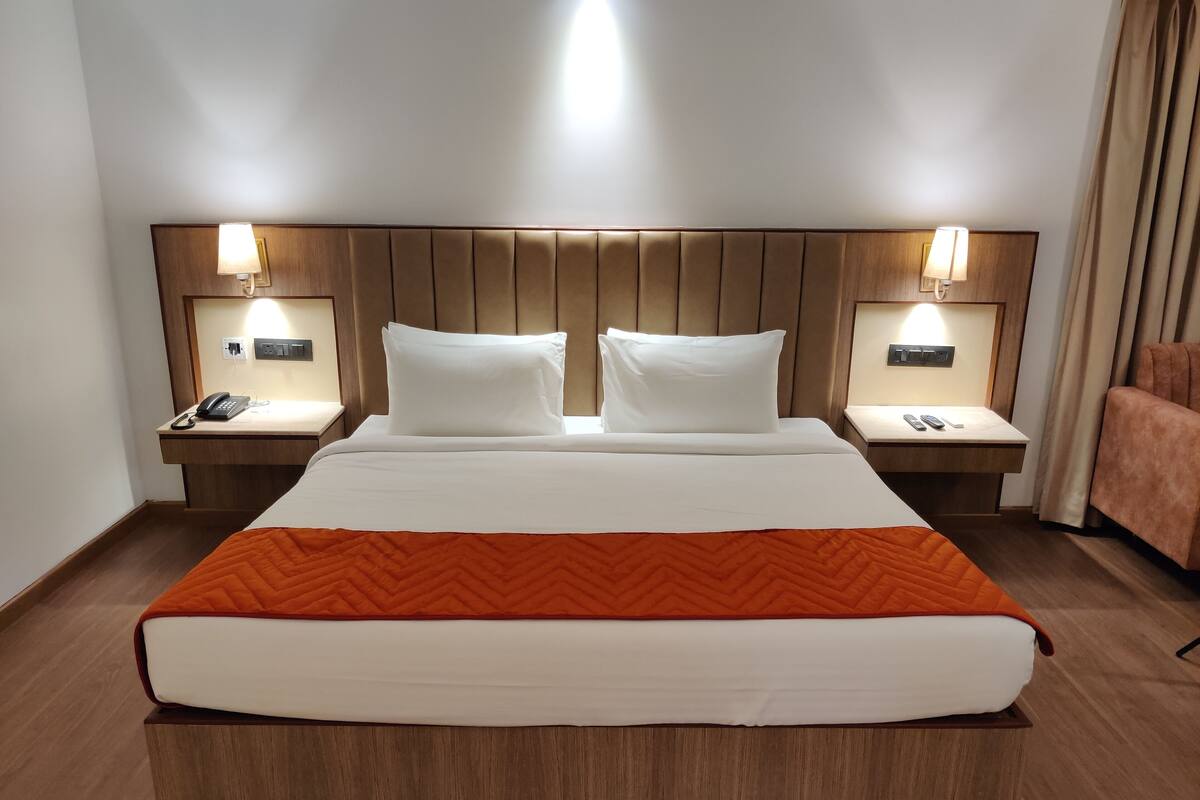 A hotel room with a large bed, two bedside tables with lamps, a telephone, and a remote control.