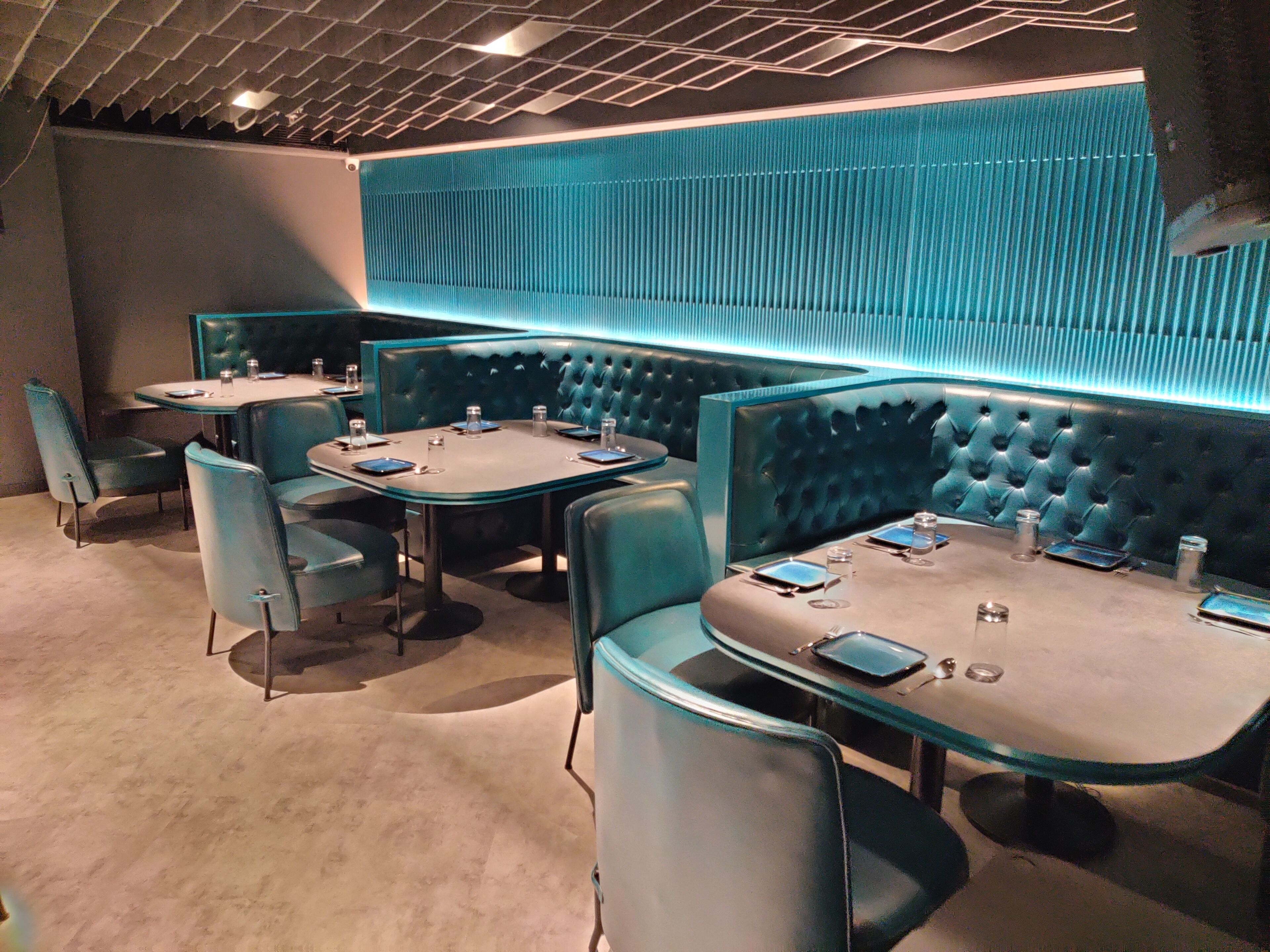 A modern restaurant with booth seating and a blue accent wall.