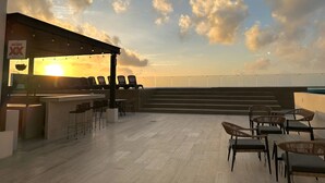 An outdoor seating area with chairs and tables, a bar, and a view of the sky with clouds. - Modern Pool View New Condo Gym Jacuzzi (Playa del Carmen)