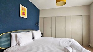A bedroom with a bed, a wardrobe, and a wall-mounted light fixture. - Glynne Street by Switchback Stays (Cardiff)