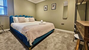 Un dormitorio con una cama, un tocador, un espejo y dos cuadros en la pared.