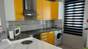 A kitchen with a microwave, stove, sink, and washing machine. - Orchard Apartment (Lucena)