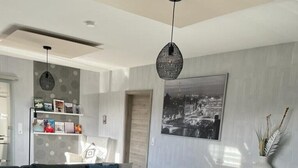 Un salon moderne avec un canapé gris, une table basse en verre, un pouf en tricot et une commode au design minimaliste.