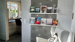 Un salon moderne avec un mur gris à motifs, un fauteuil blanc orné d’un coussin à motifs, une petite table d’appoint blanche et un tapis rond.