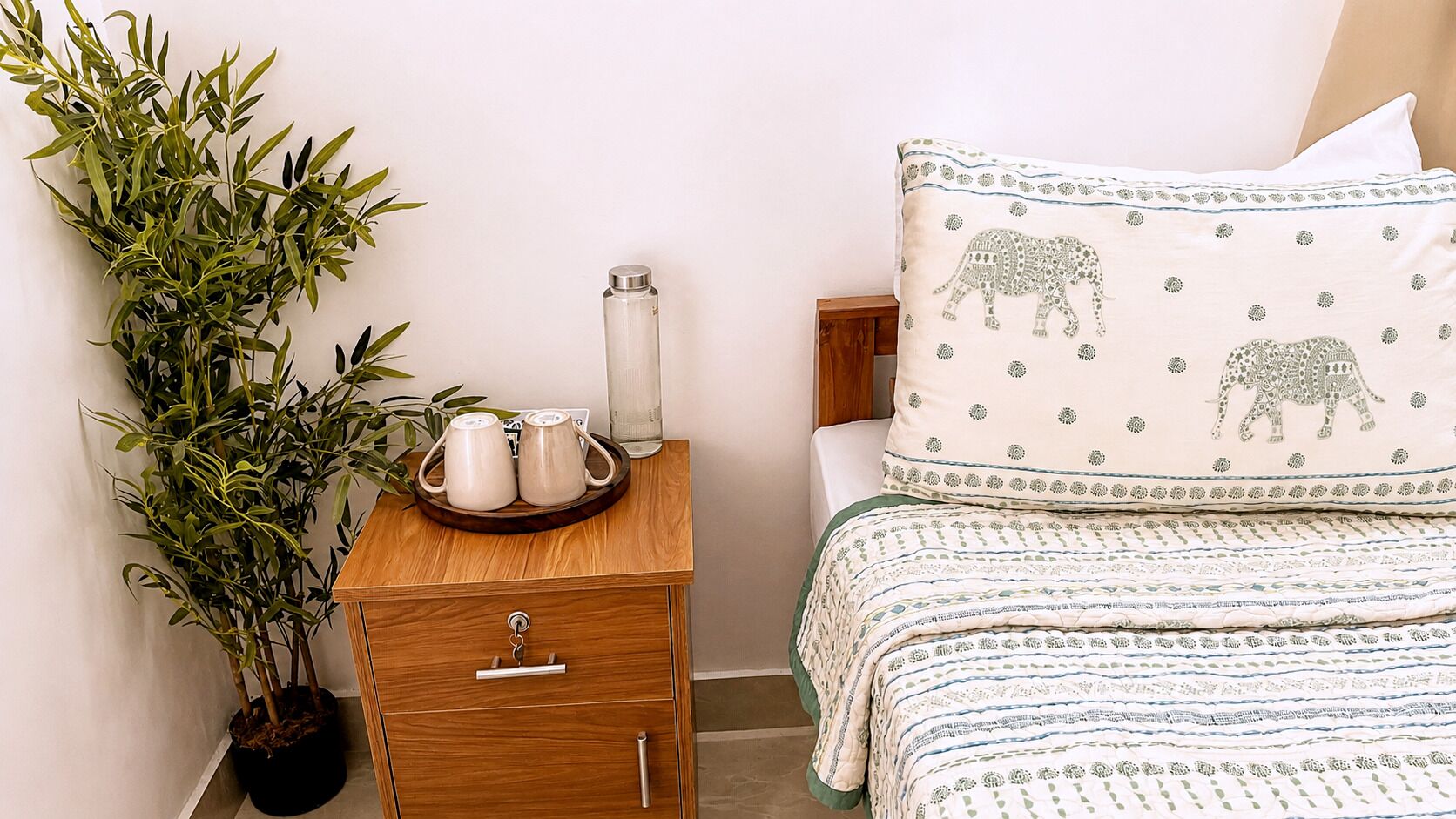 Een slaapkamer met een bed, nachtkastje en een kamerplant.