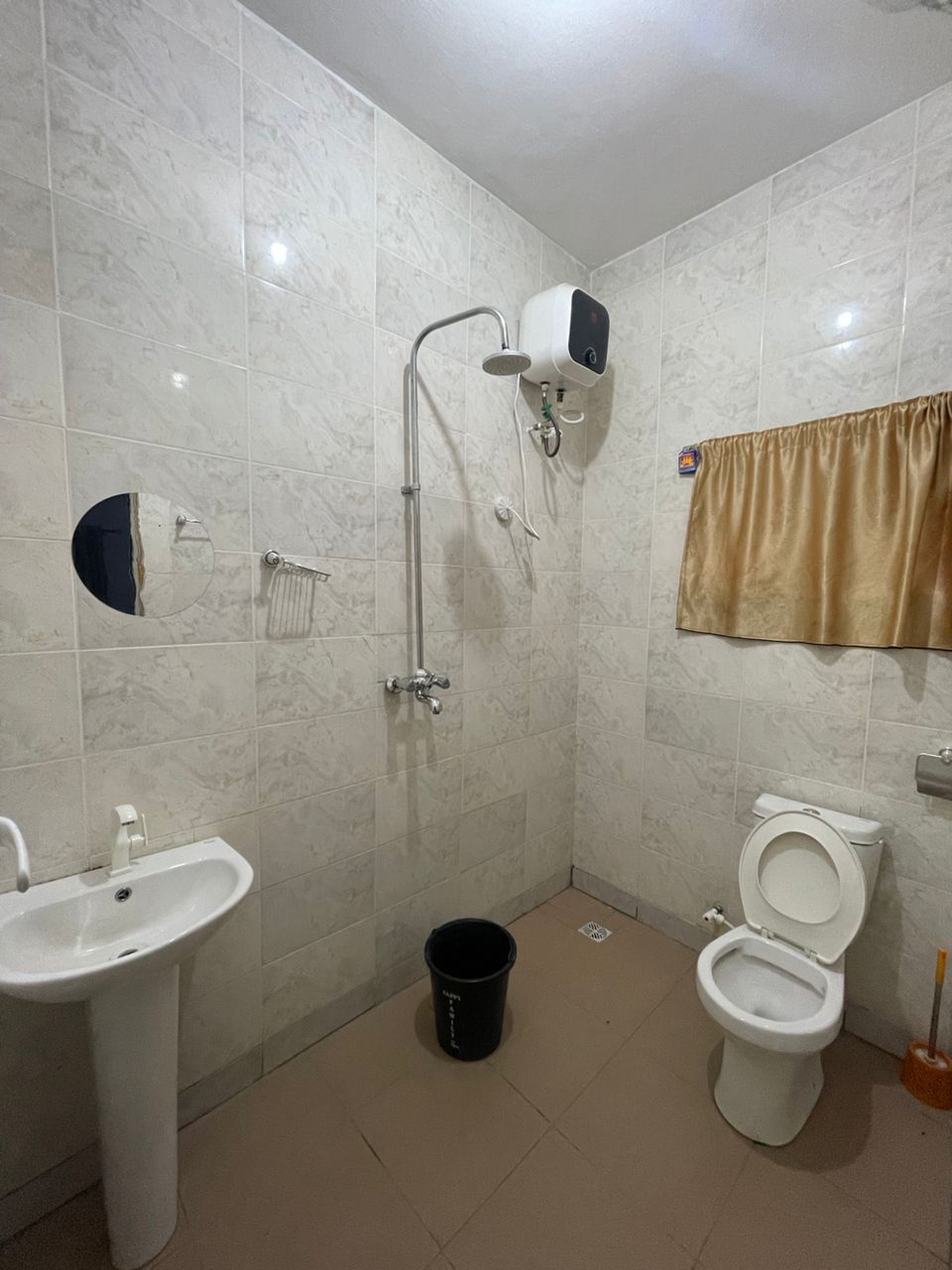 Casa de banho com lavatório, sanita, chuveiro e porta-toalhas.