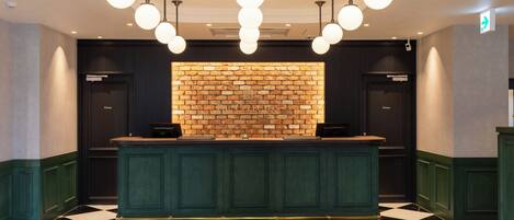 A reception area with a check-in counter, a brick wall, and a black and white checkered floor.