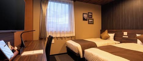 A hotel room with two beds, a desk with a computer, a TV, and a window with curtains.