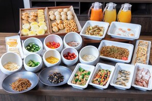 Varie pietanze e bevande disposte su un tavolo, tra cui pane, uova, noodles e insalate.