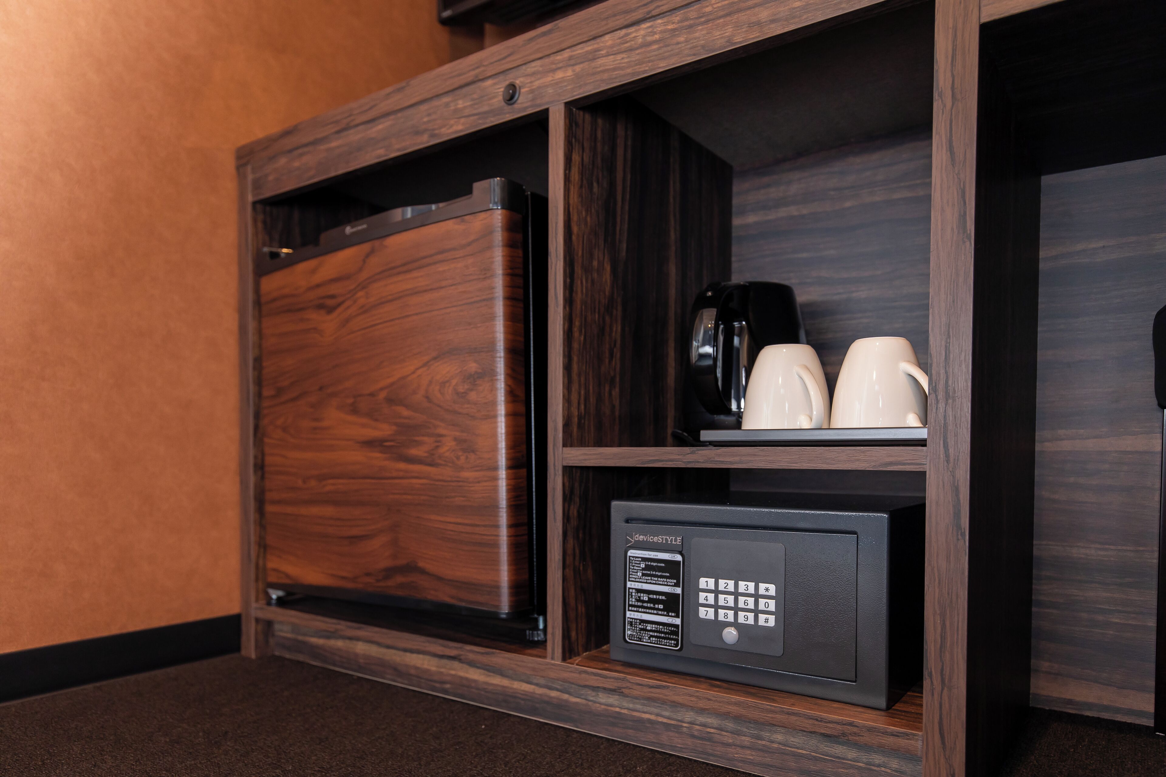 Minibar com cafeteira, duas chávenas e frigorífico.