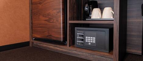 Minibar com cafeteira, duas chávenas e frigorífico.